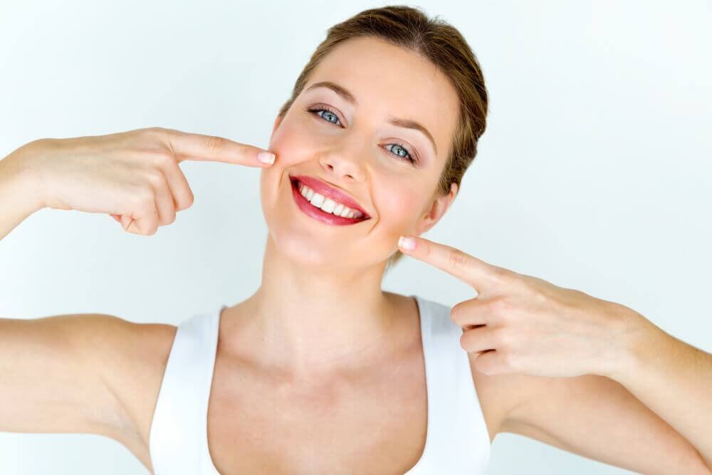 Woman pointing at her perfect smile.